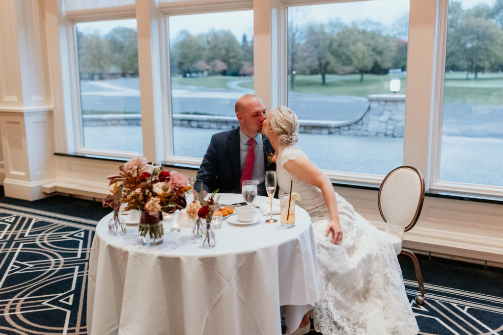 bride and groom kissing at sweetheart table at midland country club