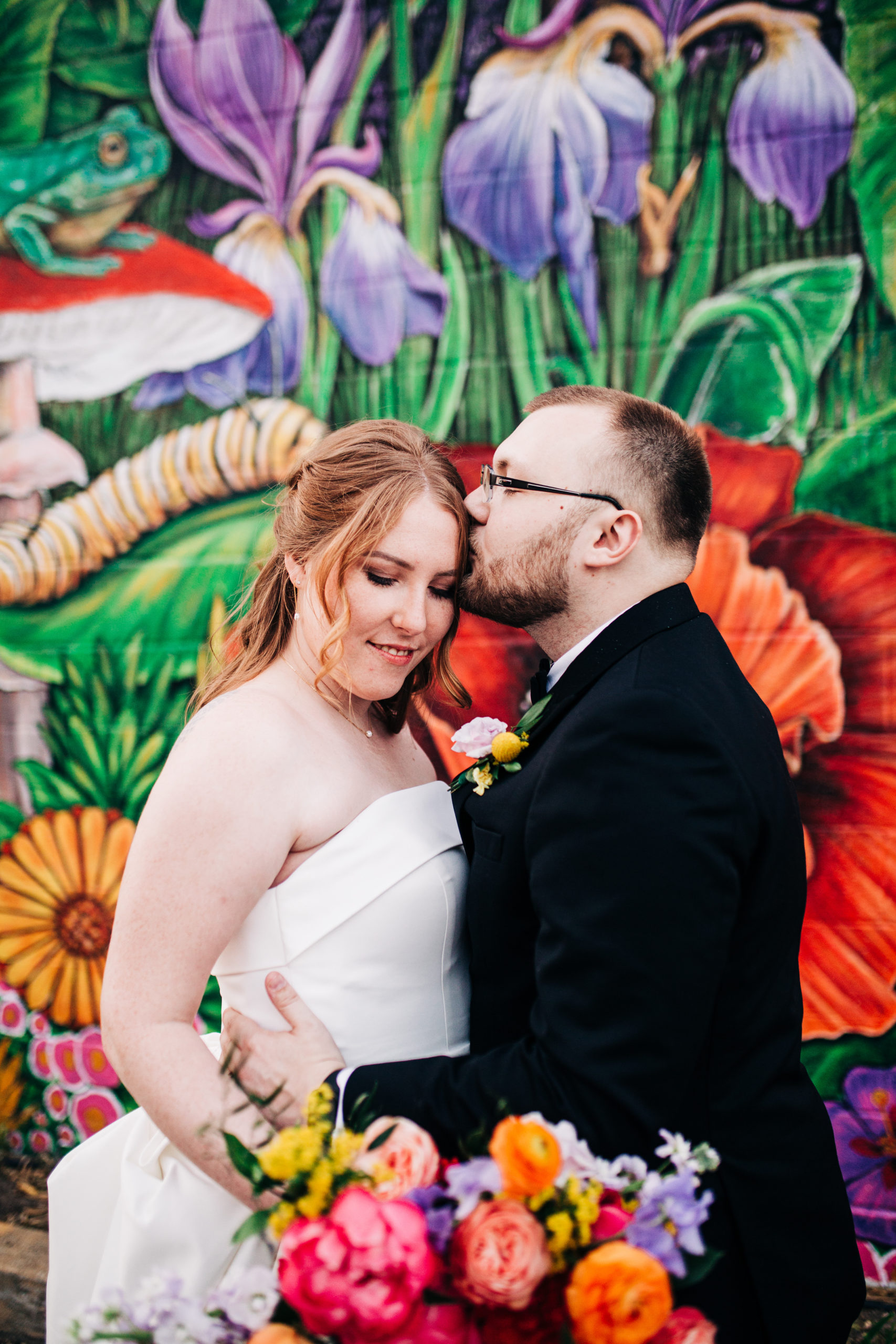 bride and groom in front of floral mural wall